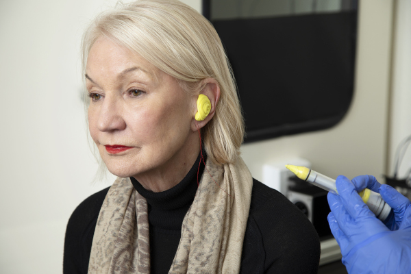 Audiologist making impressions of the ear for custom ear plug fitting.